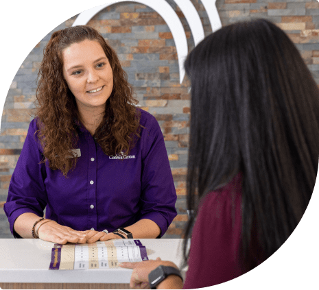 Bank teller in purple shirt smiling at customer in pink shirt